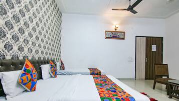 A hotel room with two beds, a wooden headboard, a patterned wallpaper, a framed picture on the wall, and a wooden door.