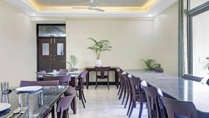 A dining area with a long table, chairs, and a ceiling fan. - Hotel Ravi Residency (Bharatpur)