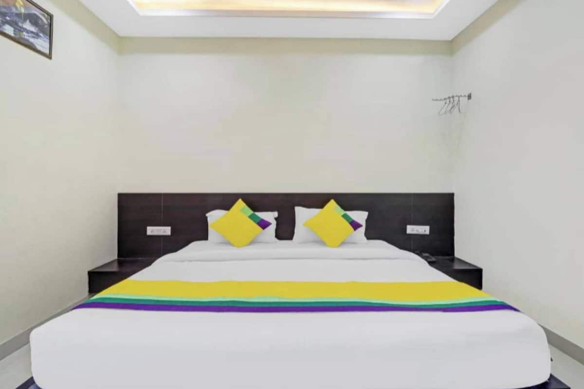 A hotel room with a neatly made bed, a nightstand, and a ceiling light fixture.