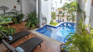 A pool area with lounge chairs, a small pool, and various plants.