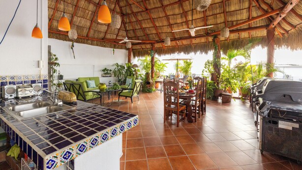 A spacious kitchen with a tiled backsplash, a dining area with a wooden table and chairs, and a grill station.