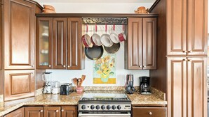 A kitchen with wooden cabinets, a stainless steel stove, and a coffee maker.