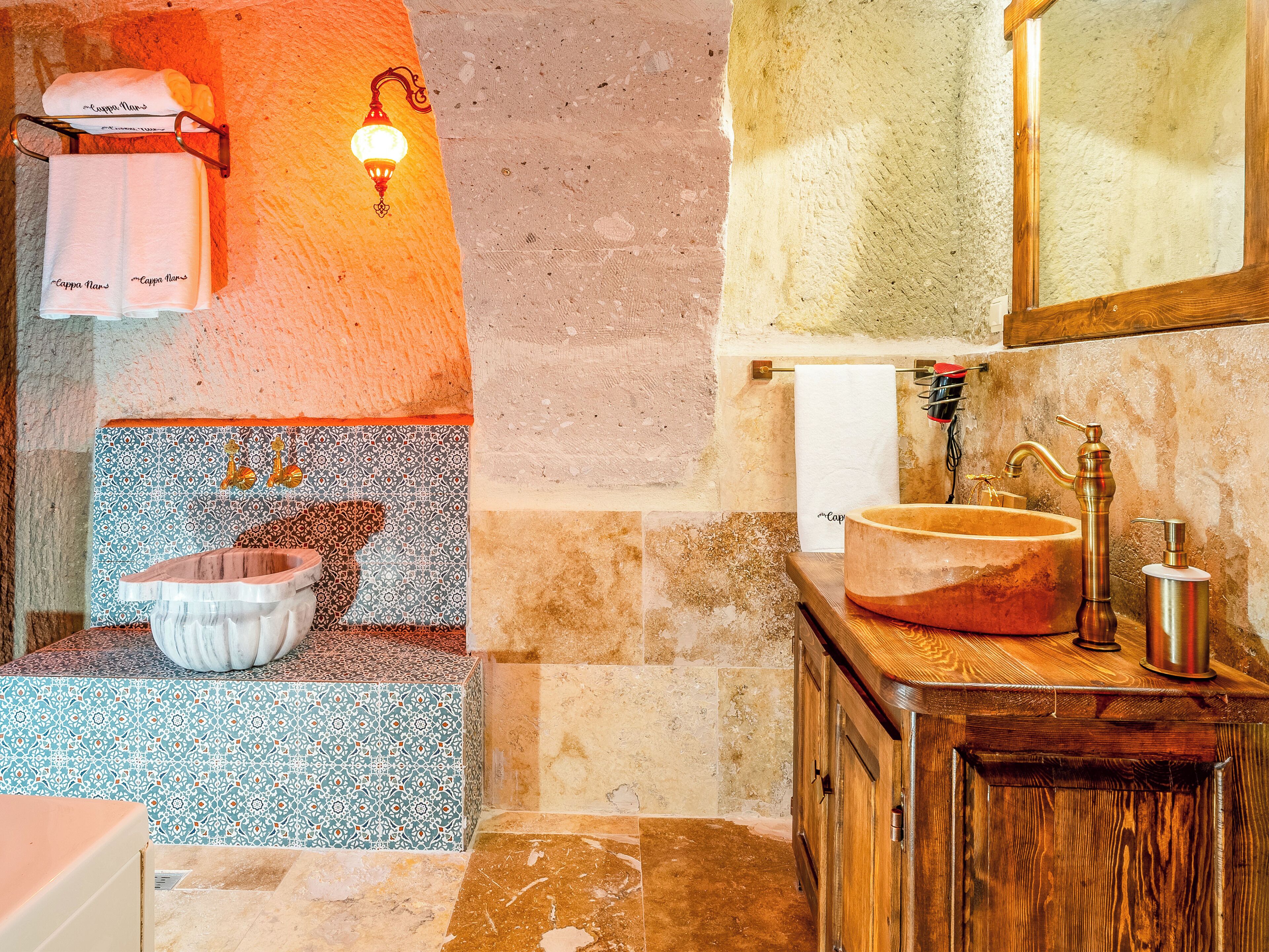 A bathroom with a marble sink, a wooden vanity, a mirror, and a wall-mounted towel rack.