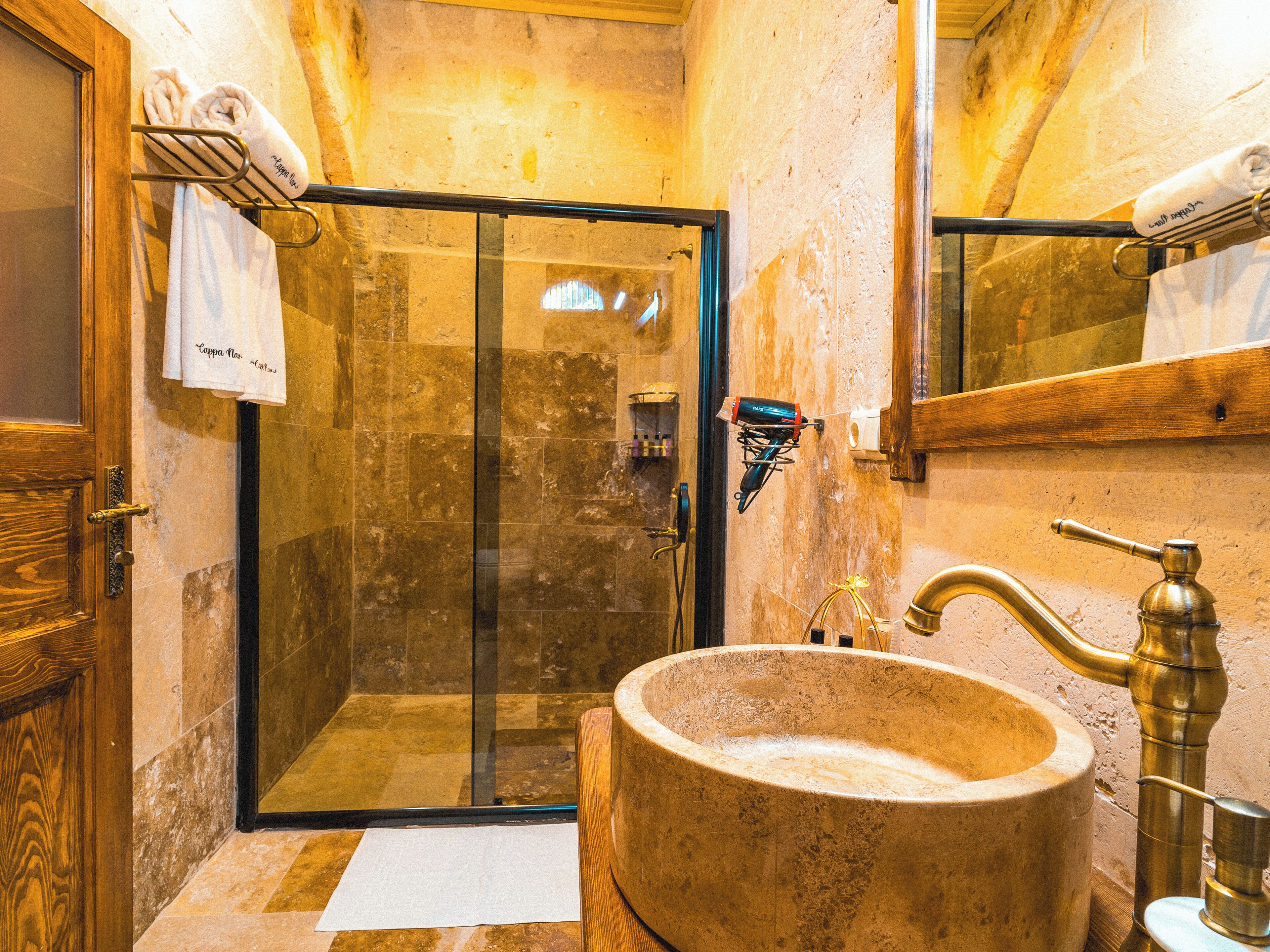 A bathroom with a stone sink, a glass shower enclosure, and a wooden door.