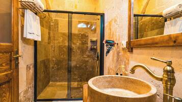 A bathroom with a stone sink, a glass shower enclosure, and a wooden door.