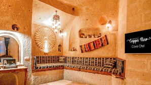 Ein gemütlicher, gut beleuchteter Raum mit einem traditionellen Sofa, einem dekorativen Teppich und einem an der Wand befestigten Schild.