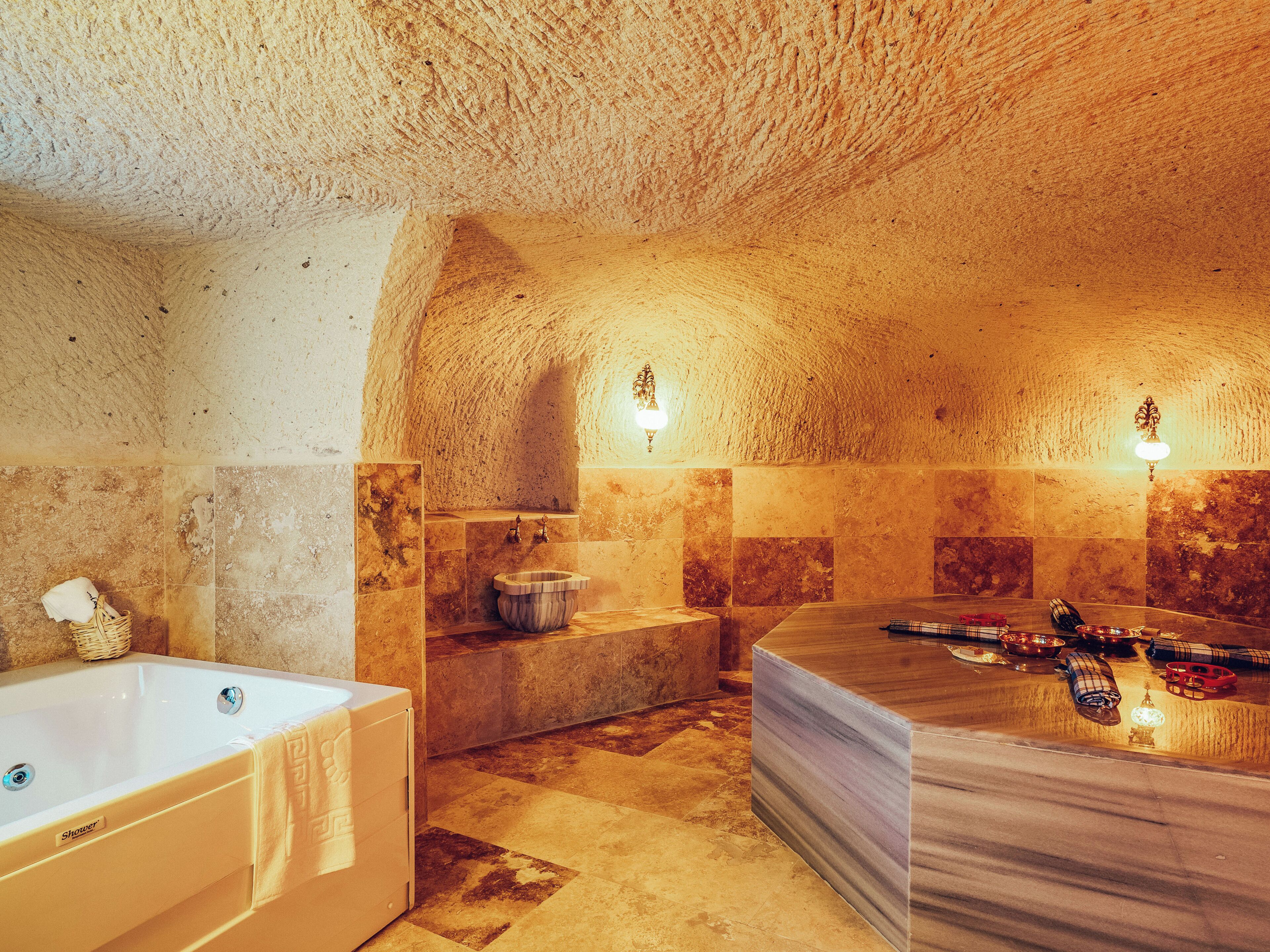 A bathroom with a bathtub, a large mirror, and a sink.