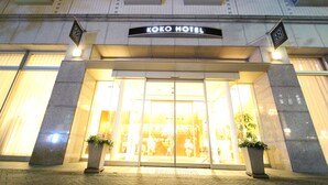 Der Eingang des Koko Hotels mit Glasfassade und Pflanzen in Töpfen.