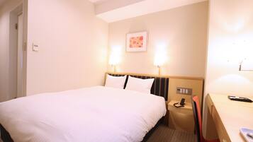 A hotel room with a large bed, bedside lamps, a desk, and a chair.