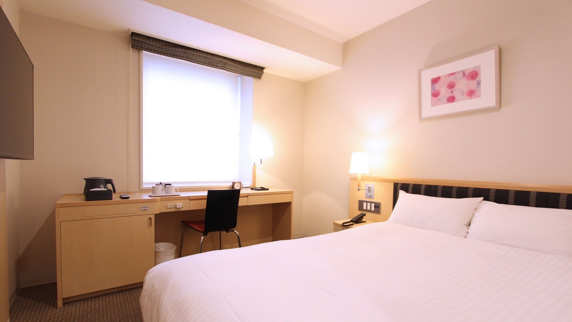 Habitación de hotel con cama, escritorio, silla y ventana con persianas.