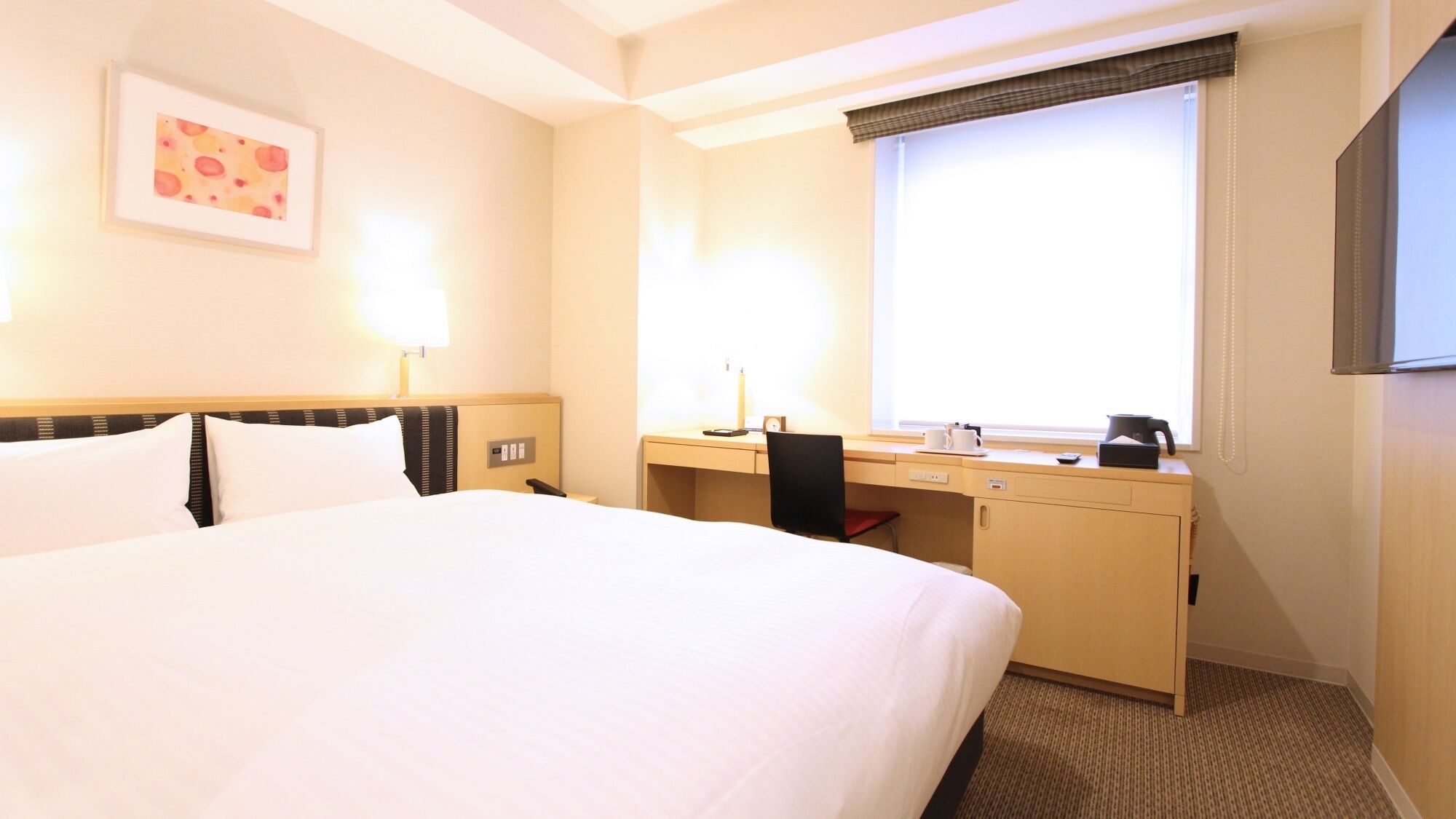 Habitación de hotel con cama, escritorio, silla y ventana con vistas.