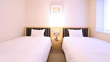 A hotel room with two single beds, a bedside table with a lamp, and a small painting on the wall.