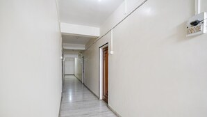 Un pasillo largo y estrecho con paredes blancas y piso de mármol.