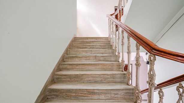Una escalera de mármol con barandillas blancas ornamentadas y una barandilla de madera.