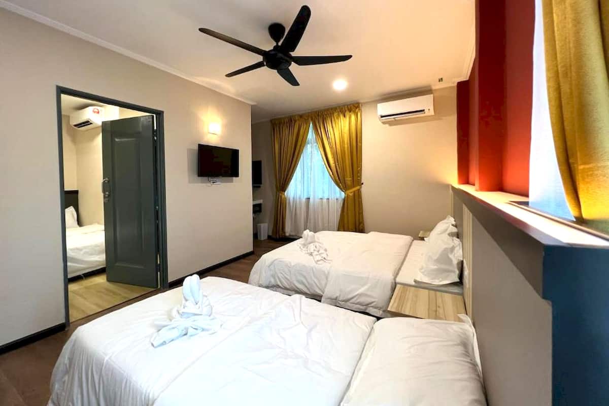 A hotel room with two beds, a ceiling fan, a TV, and a window with curtains.