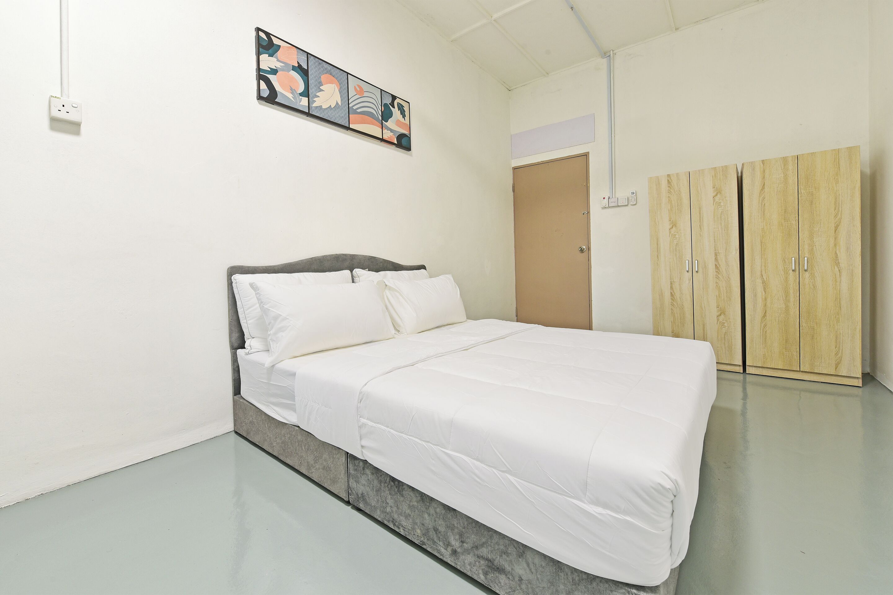 A bedroom with a bed, a wardrobe, a painting, and a door.