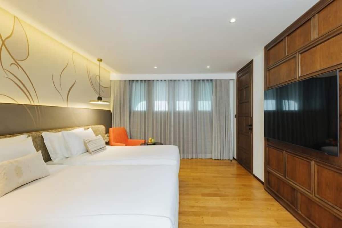 Ein Hotelzimmer mit einem großen Bett, einem Fernseher, Holzvertäfelung und einem Fenster mit Vorhängen.