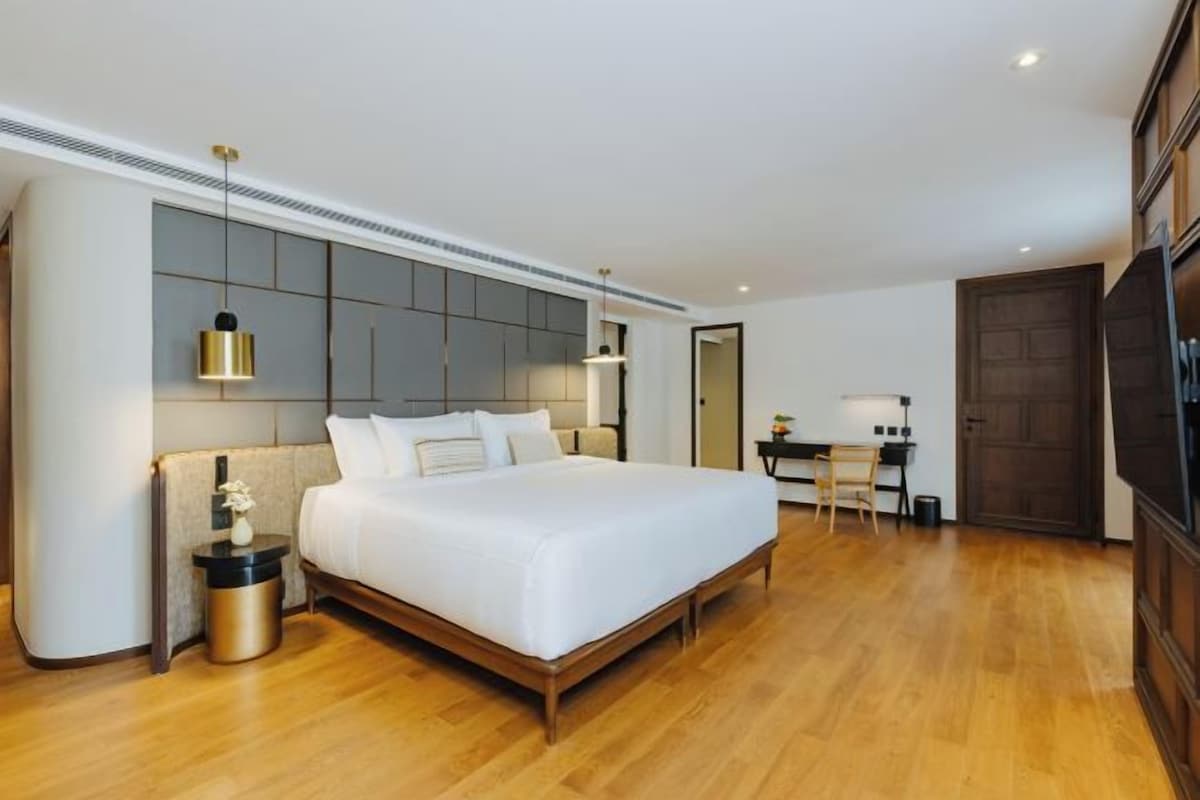 Quarto de hotel moderno com uma cama grande, uma escrivaninha e uma televisão.