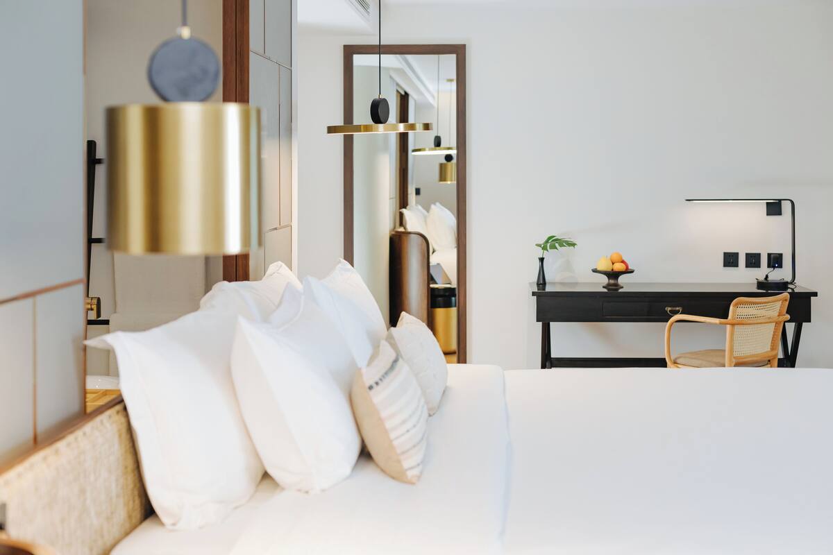 Ein modernes Hotelzimmer mit einem ordentlich bezogenen Bett, einem Schreibtisch mit Stuhl und einem Spiegel.