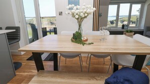 Ein Essbereich mit einem Holztisch, weißen Stühlen und einer Vase mit weißen Blumen.