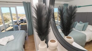 Ein Schlafzimmer mit zwei Betten, einem großen Spiegel und Blick ins Freie.