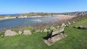 Ein Küstenblick mit einer Bank, die auf einen Strand und eine Stadt im Hintergrund blickt.