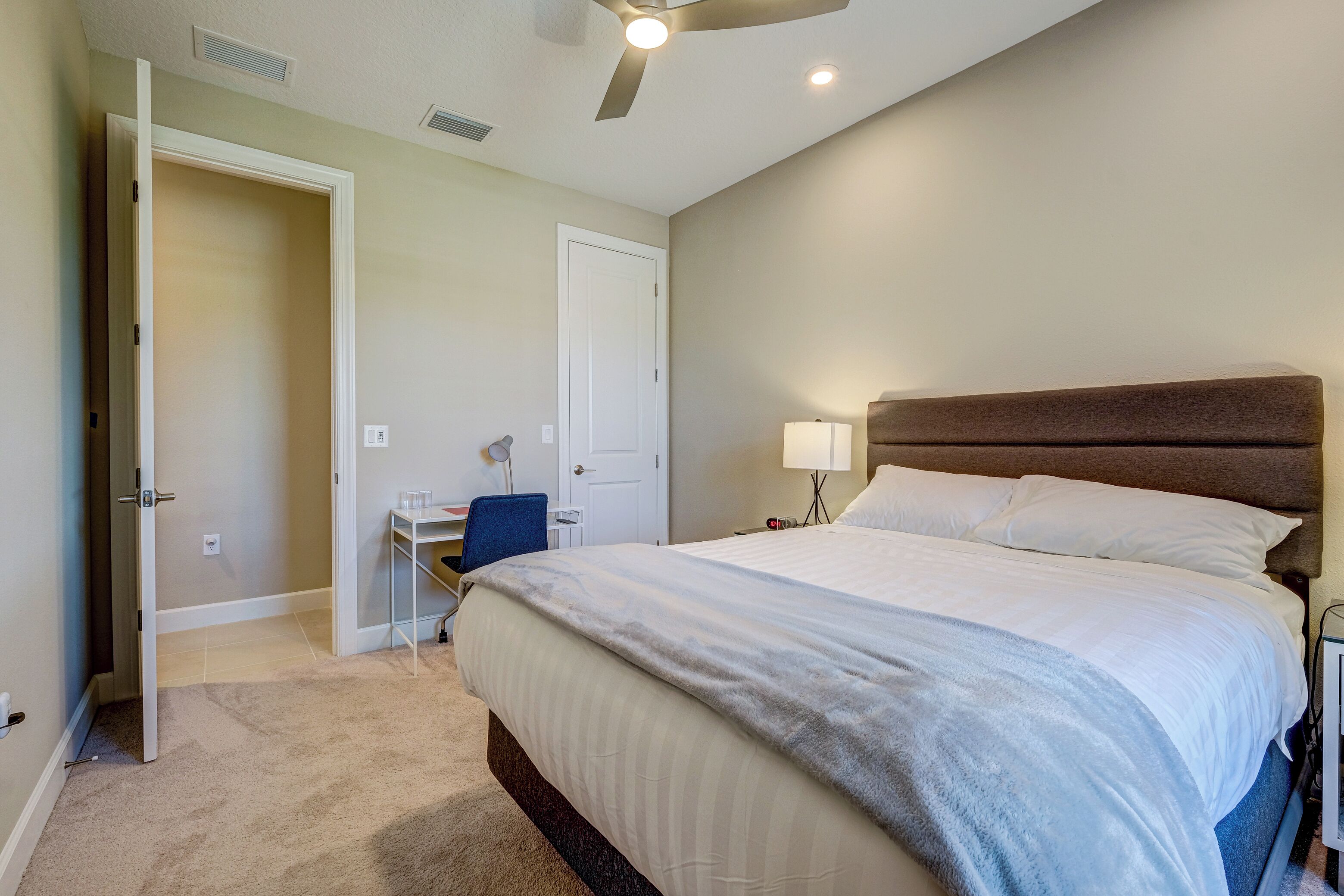 A bedroom with a bed, a desk, and a chair.