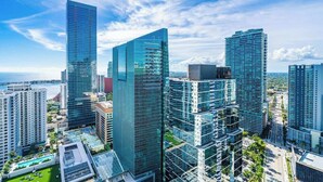 Paisagem urbana com edifícios modernos e altos, incluindo um arranha-céu de vidro imponente e uma combinação de construções residenciais e comerciais.