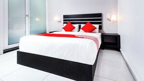 A modern bedroom with a large bed, two nightstands, and a sliding glass door. - Collection O 88 Hotel (Malacca City)
