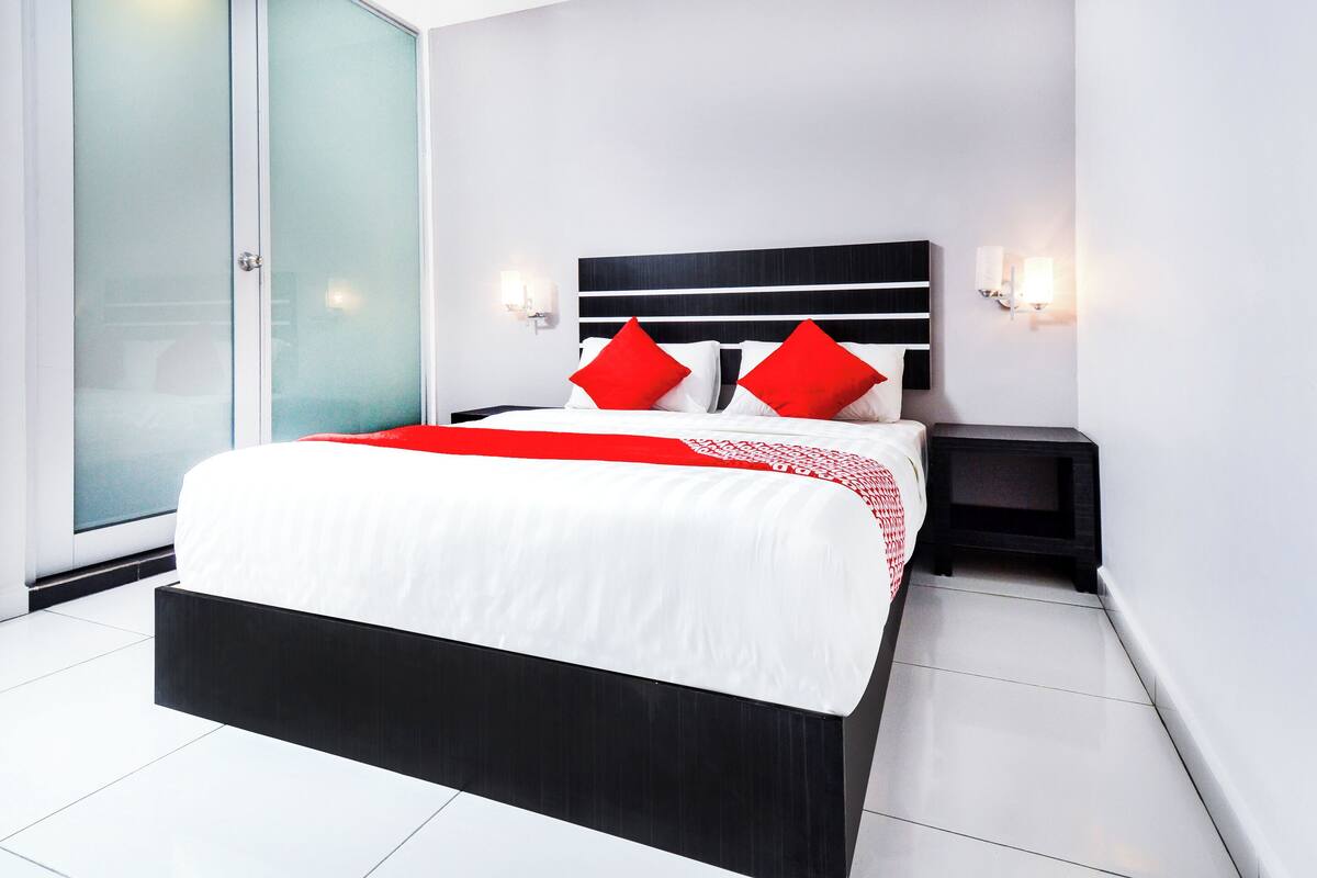 Een moderne slaapkamer met een groot bed, twee nachtkastjes en een schuifdeur van glas.
