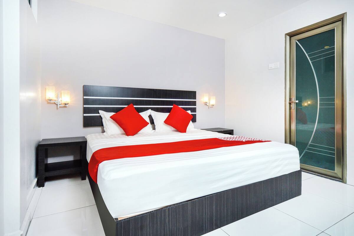 Een moderne hotelkamer met een groot bed, twee nachtkastjes en een glazen deur.