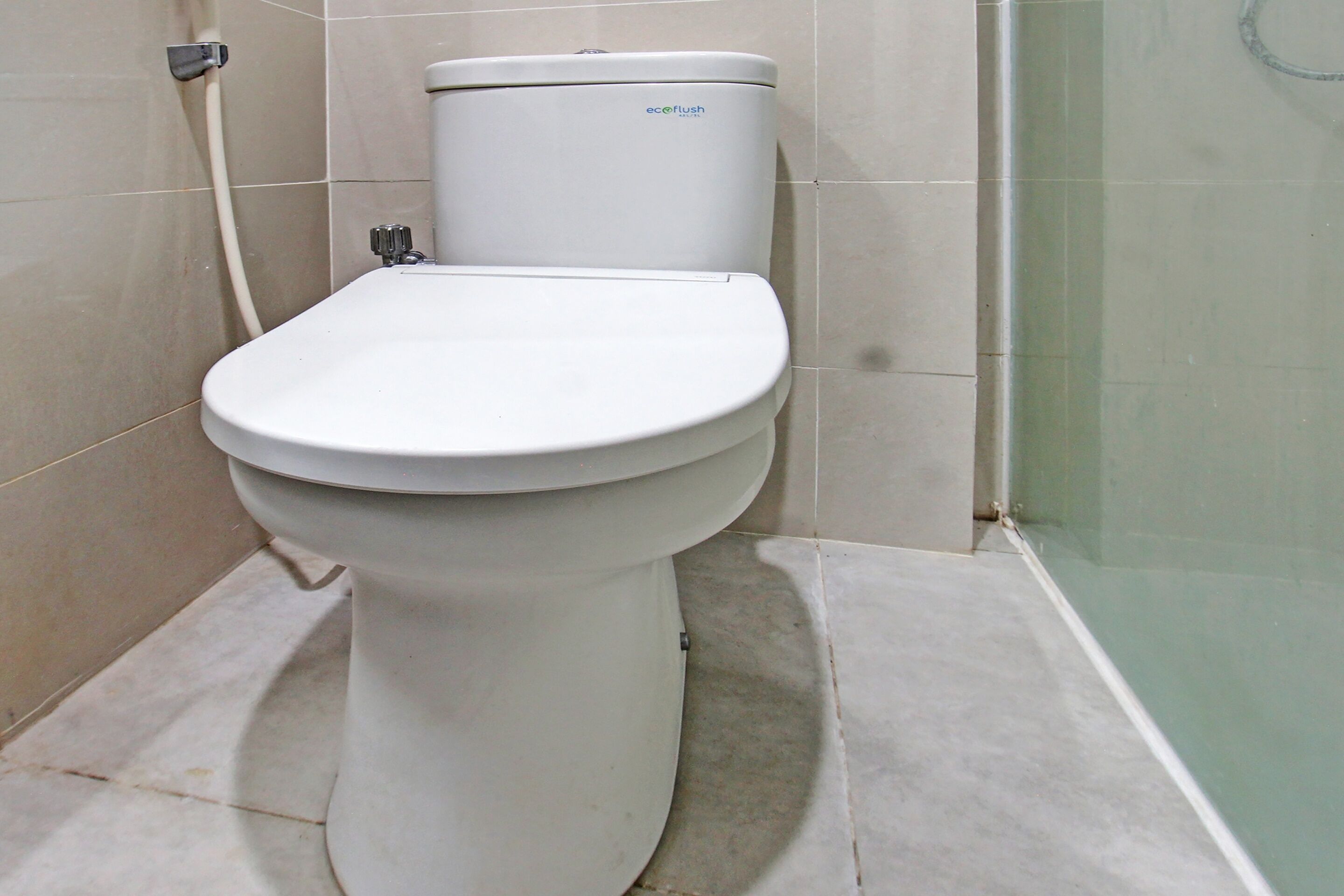 A white toilet with a visible brand label, a visible pipe, and a tiled floor.