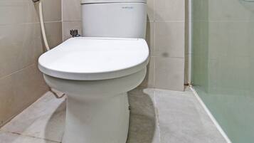 A white toilet with a visible brand label, a visible pipe, and a tiled floor.