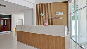 A reception desk with a wooden panel and a marble counter, a sign reading "TRAINING CENTER", and a logo for the Islamic Development Bank. - Capital O 92604 Hotel Uin Syariah Near Kampus UIN Mataram (Mataram)