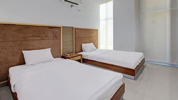 A hotel room with two beds, a wooden headboard, a nightstand, and a window providing natural light.