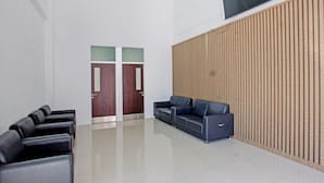 A waiting area with black leather chairs, a blue sofa, and a wooden panel wall. - Capital O 92604 Hotel Uin Syariah Near Kampus UIN Mataram (Mataram)