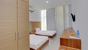 A modern hotel room with two wooden beds, a wooden desk, and a large window providing natural light. - Capital O 92604 Hotel Uin Syariah Near Kampus UIN Mataram (Mataram)