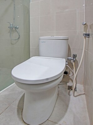 A white toilet with a tank, a shower head, and a pipe.