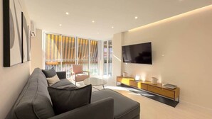 A modern living room with a sofa, a TV, a small table, and a cabinet.