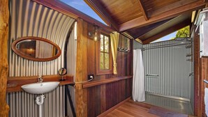 Baño de cabaña de madera con lavabo, espejo y ducha.