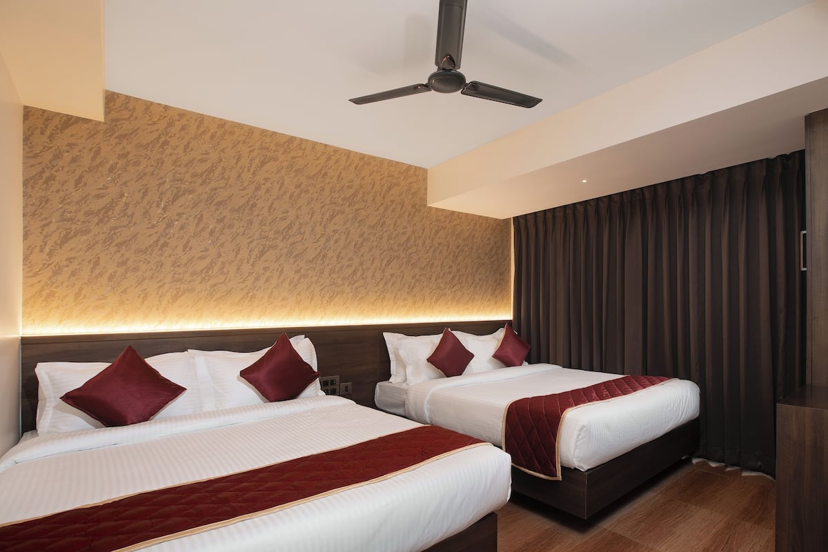 A hotel room with two beds, a ceiling fan, and a large window with curtains.