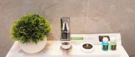 A bathroom sink with a potted plant, a dental kit, and two bottles of soap.