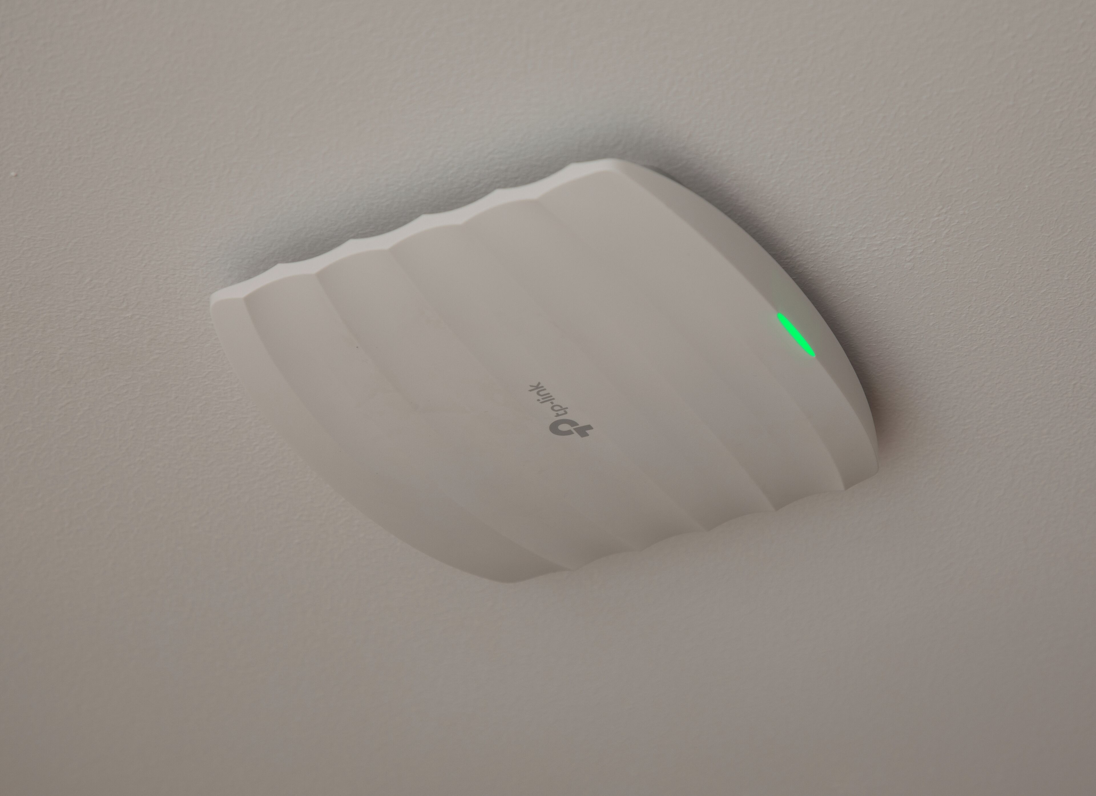 Un appareil rectangulaire blanc, fixé au mur, doté d’un indicateur lumineux vert.