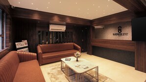 Una sala de estar moderna con un sofá de cuero marrón, una mesa de centro con revistas y un televisor montado en la pared.