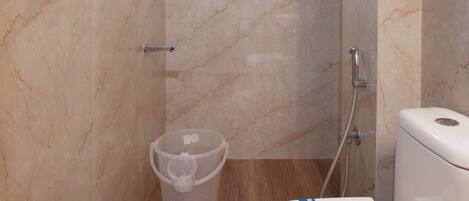 Un baño moderno con ducha, inodoro y un cubo de basura.