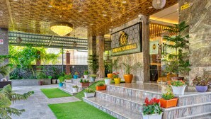 Um saguão de hotel com uma recepção de mármore, um candelabro e plantas em vasos.