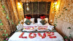 Uma cama com almofadas em formato de coração e uma decoração de flores com a palavra 'LOVE'.