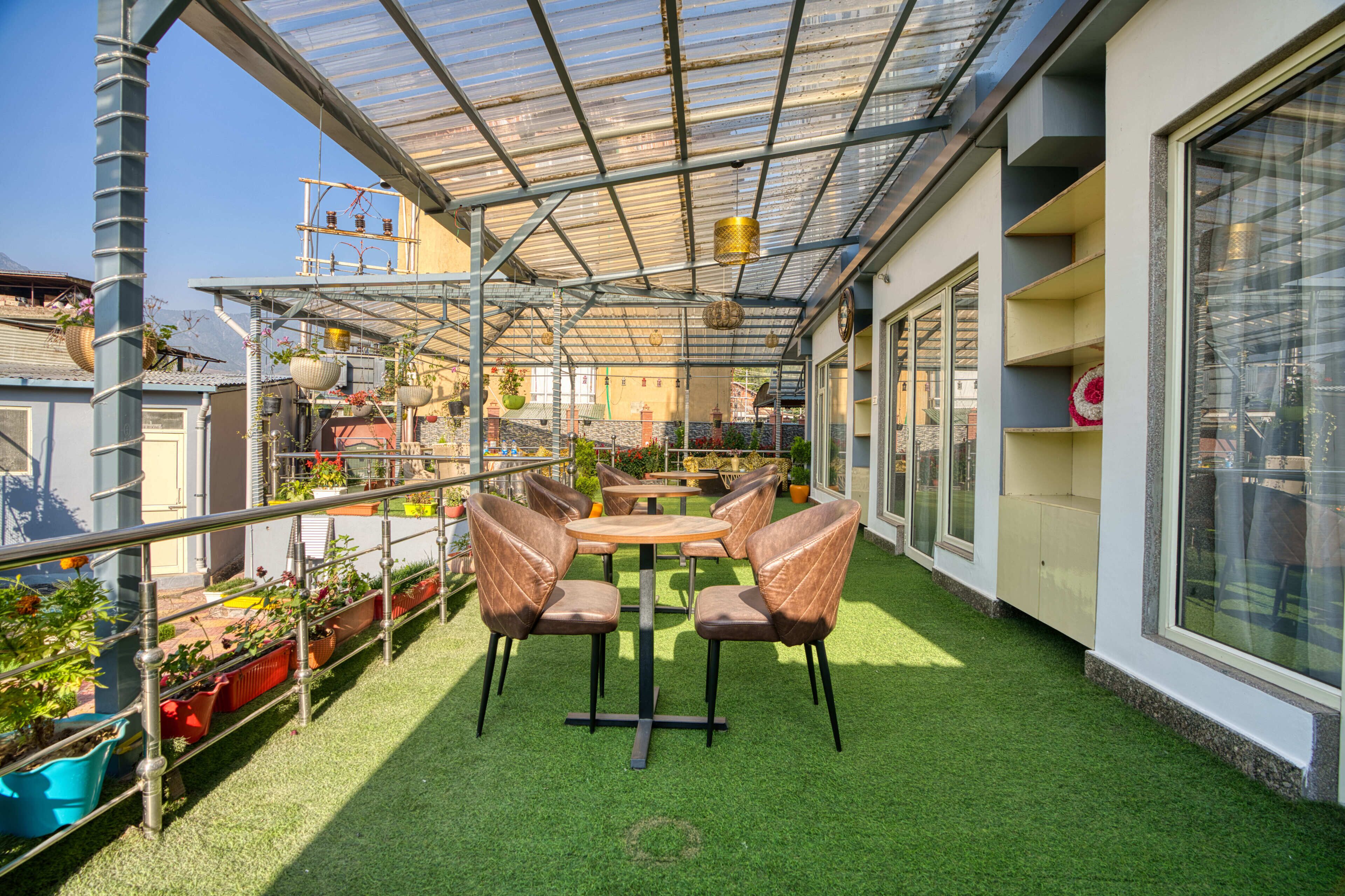 A rooftop garden with artificial grass, a table with chairs, and potted plants.
