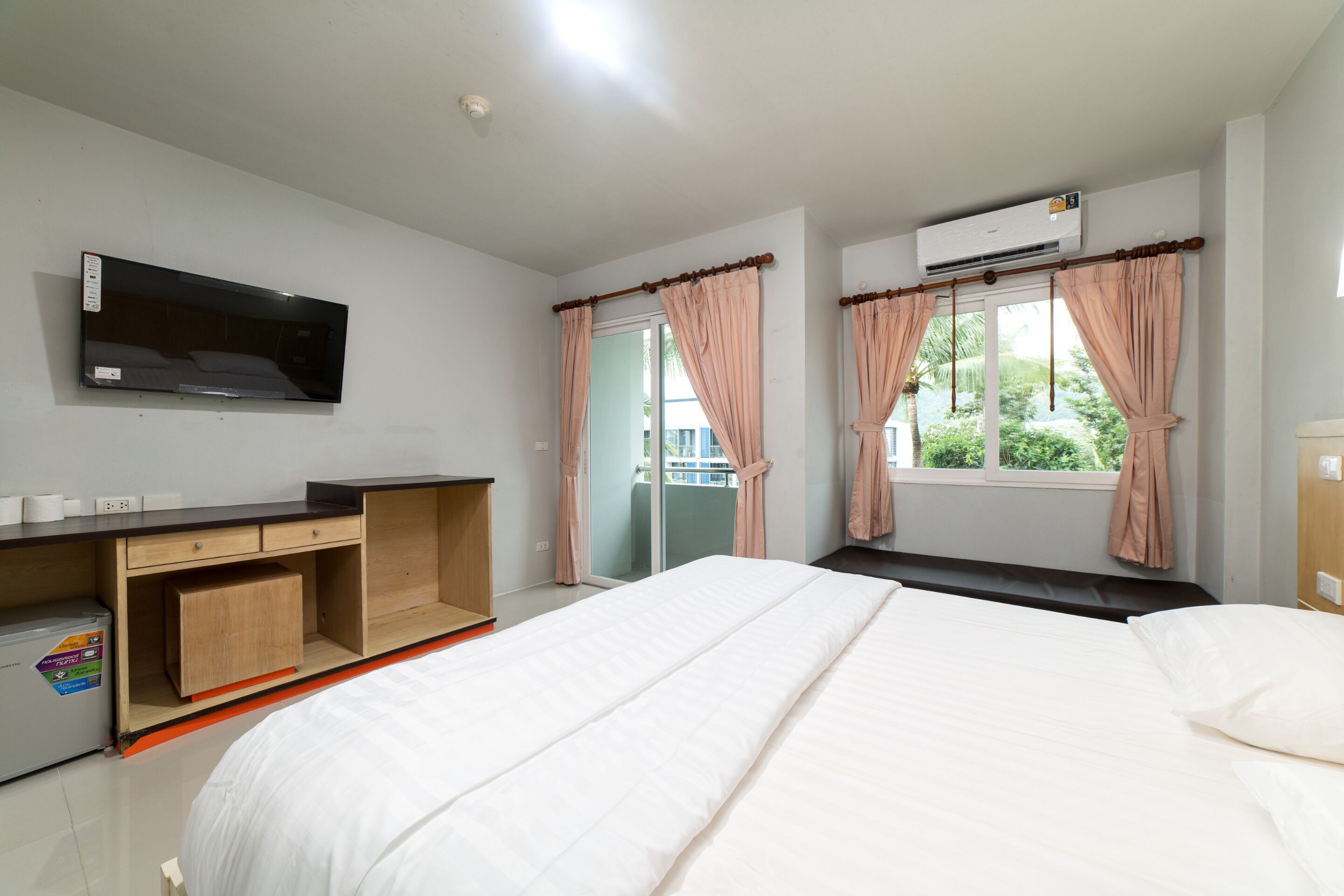 Un dormitorio con cama, escritorio, televisor y aire acondicionado.