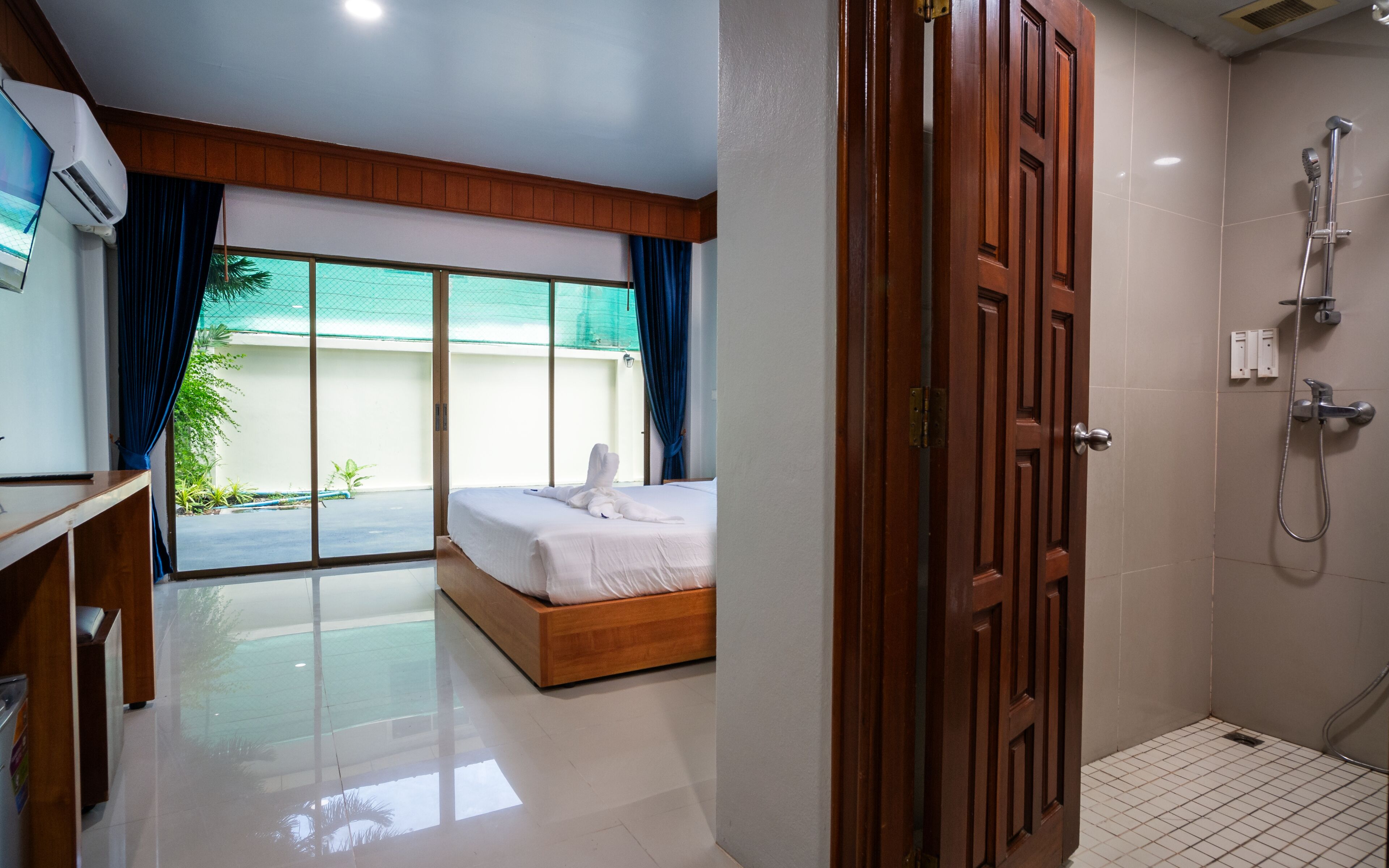 A hotel room with a bed, a shower, and a view of a pool and greenery.